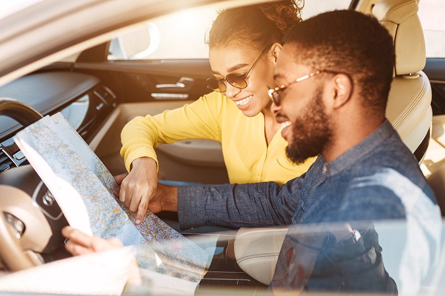Personal Insurance - Closeup of Young Couple Looking Over Map in Car and Getting Ready to Take a Road Trip in New Vehicle